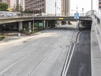 two street signs next to each other on a highway underpass with buildings in the background
