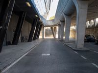 a long walkway in an empty area with parked cars parked along the road and people on bikes