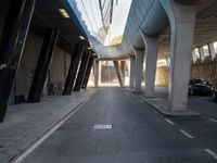 a long walkway in an empty area with parked cars parked along the road and people on bikes