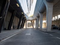 a long walkway in an empty area with parked cars parked along the road and people on bikes