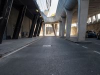 a long walkway in an empty area with parked cars parked along the road and people on bikes