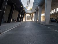 a long walkway in an empty area with parked cars parked along the road and people on bikes