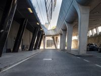 a long walkway in an empty area with parked cars parked along the road and people on bikes