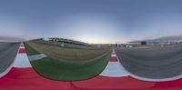 a panoramic view of the racetrack with an airplane flying in the background and another person standing on the run way