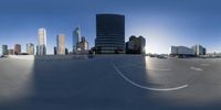 an oval view shows some very tall buildings in the city from across a parking lot