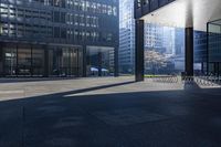 a long bench on concrete surrounded by tall buildings in a big city parking lot with blue sky