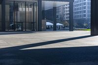 a long bench on concrete surrounded by tall buildings in a big city parking lot with blue sky