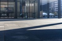 a long bench on concrete surrounded by tall buildings in a big city parking lot with blue sky