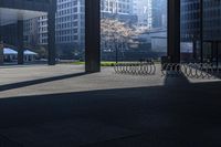 a long bench on concrete surrounded by tall buildings in a big city parking lot with blue sky