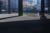 a long bench on concrete surrounded by tall buildings in a big city parking lot with blue sky