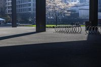 a long bench on concrete surrounded by tall buildings in a big city parking lot with blue sky