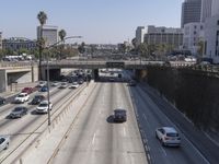 the view of a highway and a street from the freeway bridge above it with several cars on it