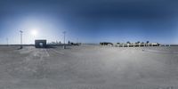 an empty parking lot near a street and buildings with some palm trees on top of it