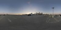 the view from the parking lot shows the empty lot in the foreground with an orange sun setting