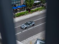 a woman walking by a silver car on the road by a sidewalk and cars parked along the street