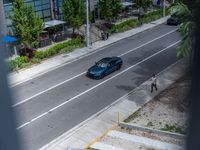 a woman walking by a silver car on the road by a sidewalk and cars parked along the street