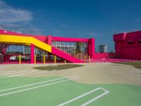 a person standing on top of a basketball court next to a pink and yellow building