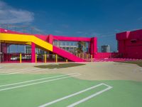 a person standing on top of a basketball court next to a pink and yellow building