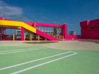a person standing on top of a basketball court next to a pink and yellow building
