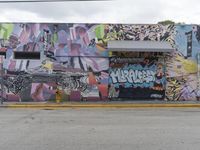 a large building covered with graffiti sitting on the side of a street next to a road