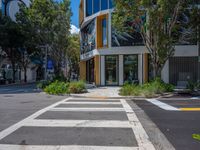 the empty cross walk way between two large buildings in the city park area of an intersection with trees, bushes, and a fire hydrant