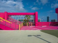 a pink building with staircases and yellow railing on the outside area of the building