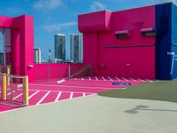 the court outside is in a pink building and blue is bright pink with white paint