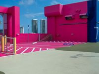 the court outside is in a pink building and blue is bright pink with white paint