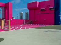 the court outside is in a pink building and blue is bright pink with white paint