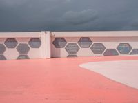 this is the end of a pink wall with colorful hexagons painted on it