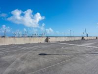 an empty parking lot with many empty vehicles parked in it in front of a wall with seagulls