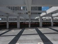 an empty parking space in a big building with many levels and lanes on it and shadows on the ground