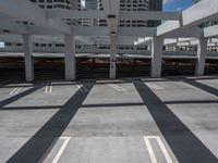 an empty parking space in a big building with many levels and lanes on it and shadows on the ground