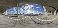 this fisheye photograph depicts a long curved walkway that links the city and mountains, with circular circles in the center