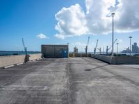 an empty parking lot with some concrete and a sky background and a blue door with white clouds above