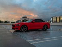 a red sports car parked at an airport parking lot with clouds in the background,