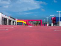 a large building with a very colorful entrance way next to a big pink gate and some street lamps