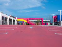 a large building with a very colorful entrance way next to a big pink gate and some street lamps
