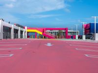a large building with a very colorful entrance way next to a big pink gate and some street lamps