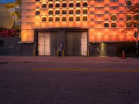 an orange building with windows on either side of it that is lit up at dusk