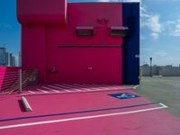 there is a parking lot with a pink building in the background and a blue building