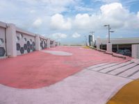 an empty parking lot has been painted red and yellow in the middle of a cloudy day