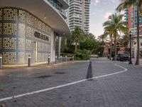 a building with lots of windows that look like a wall with letters on it, and palm trees in front of it