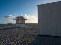 a life guard house on the beach by a body of water behind it is sand and trees