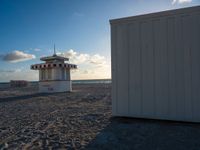 a life guard house on the beach by a body of water behind it is sand and trees