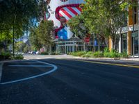 a large statue of an american flag is displayed on the side of a street with trees in the foreground