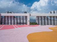 the colorful painted ground has a building in the background with a sky background and clouds