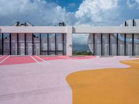the colorful painted ground has a building in the background with a sky background and clouds