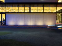 a very large white building lit by some lights from outside the windows as people walk by it