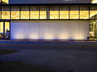 a very large white building lit by some lights from outside the windows as people walk by it